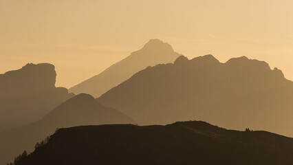 Colorful orange sky during sunrise with the silhouette of many mountains and summits in the Dolomites in Italy