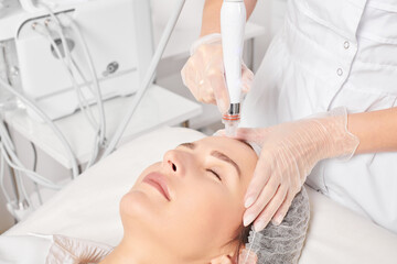 Cosmetologist makes aqua exfoliation for rejuvenation woman face skincare, anti aging cosmetic...