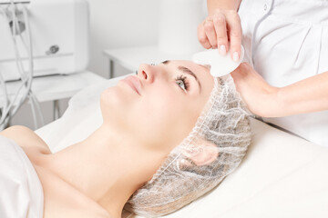Cosmetologist making facial massage with Gua Sha stone of woman face skin for lymphatic drainage,...