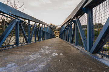Asphalted path through a narrow metallic bridge.