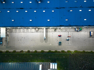 Aerial view of goods warehouse Night. Logistics center in industrial city zone from above. Aerial view of trucks loading at logistic center