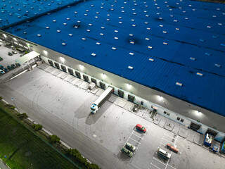 Aerial view of goods warehouse at Night. Logistics center in industrial city zone from above....