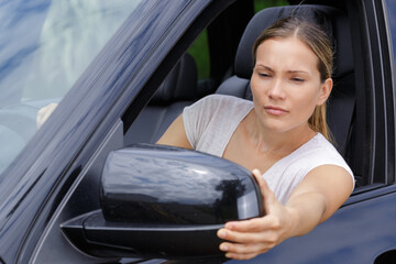 female driver adjusting side view mirror