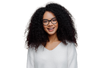 Portrait of pleasant looking smiling woman with Afro hairstyle, wears optical glasses and white sweater, has cheerful face expression, isolated over purple background. Millennial girl poses indoor
