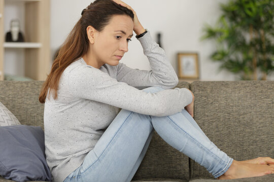 picture of a sad looking woman sitting on the sofa