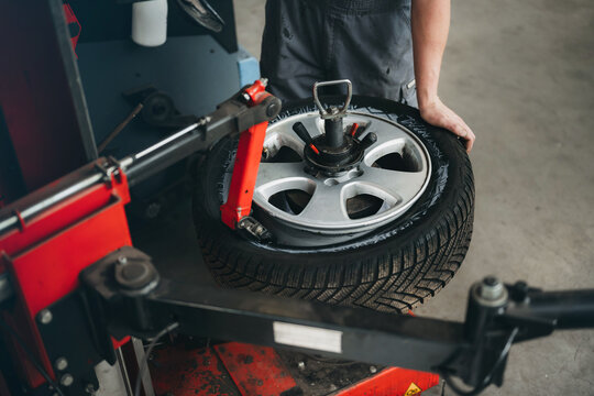 mechanic putting a tire on the wheel rim using a special machine and tool and putting tire on car