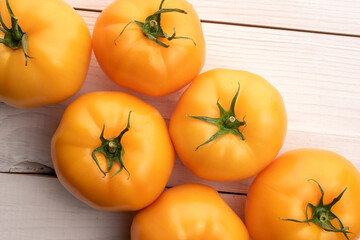 Several organic delicious, juicy tomatoes on a painted white table, top view.