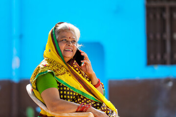 old Indian rural woman talking on smartphone at home