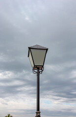 Fototapeta na wymiar Old light pole isolated under dark clouds sky