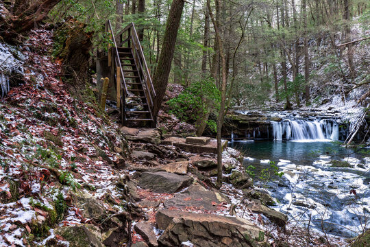 Hiking the Fiery Gizzard trail across a foot bridge by a mountain creek with snow and a waterfall. In South Cumberland State Park, Tracy City, Tennessee USA.