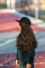 A girl in a sports tracksuit and a baseball cap in a sports center.