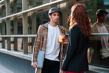 Man talking to female business colleague outside office building.