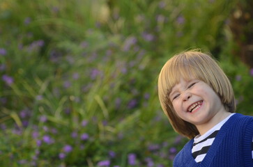 Portrait of a positive little boy. Face close-up. The child smiles sincerely. Space for text on a green background. Pleasant emotions