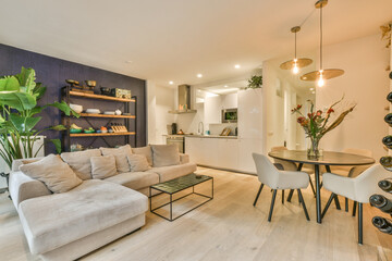 a living room with white walls and wood flooring, there is a small dining table in front of the couch