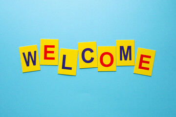 Welcome concept, inscription from yellow cubes on a wooden surface.