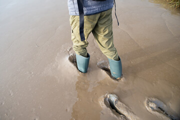 Man is walking with gumboots on the wadden sea, north sea on island Romo in Denmark, foreshore and...