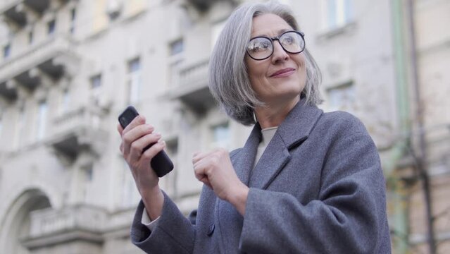 Successful woman in her 60s orders foods and goods delivery online on smartphone