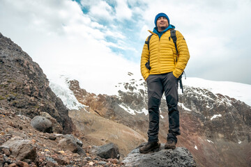 Successful man backpacker hiking in winter mountains