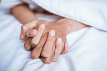 close up of a couple's hands while making love on the bed