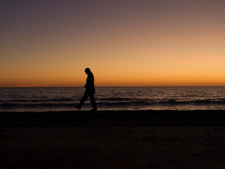 person walking on the beach at sunset