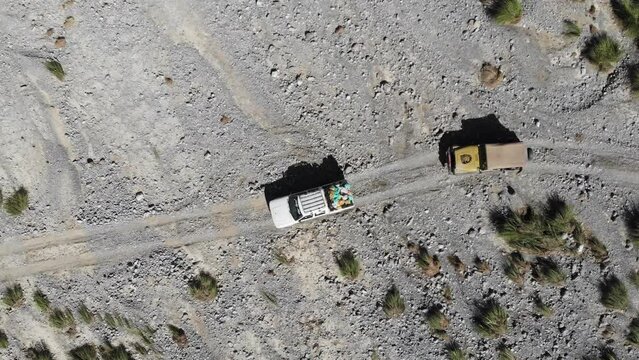Aerial top angle shot of car driving in the rocky road of mountain. Trekkers are going for trekking. 