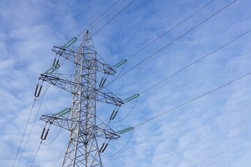 Electric power transmission against blue sky with light clouds, energy cooncept