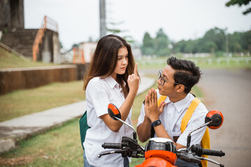 A high school student girl is annoyed by pointing her middle finger at a male student riding a...