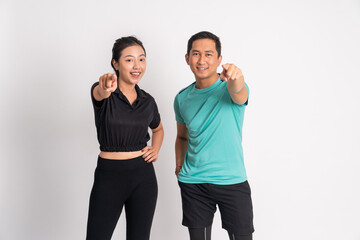 asian woman and man smiling with fingers pointing at camera on isolated background