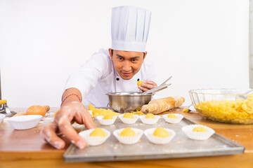 male chef carefully laying and arranging cakes on tray on isolated background