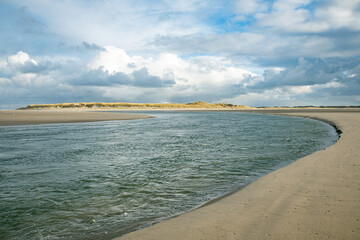 dark clouds over the sea with sunshine on the dunes near the beach