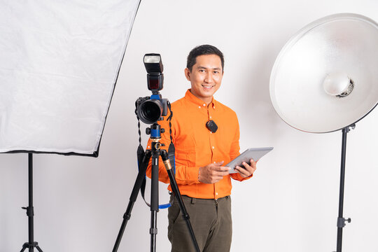 vlogger standing behind camera and holding pad with lighting equipment on isolated background