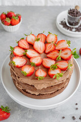 Naked chocolate cake with cream and fresh strawberries on top. Rustic style. Selective focus. Copy space.