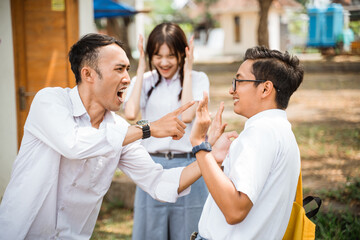 Two male high school students fighting with scared girl screaming background