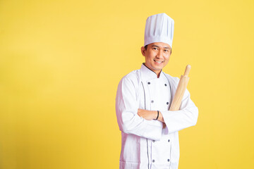 male chef with hands crossed while holding wooden rolling pin on isolated background