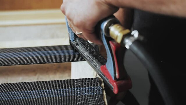 A worker makes a sofa in a furniture factory. Close-up male hands making part of sofa. Slow motion shot.