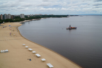 The beach on the Amazon River. On the river a ship full of Christmas decorations with nativity scene and Jesus figures and huge Christmas tree. Ponta Negra district of Manaus, Brazil.