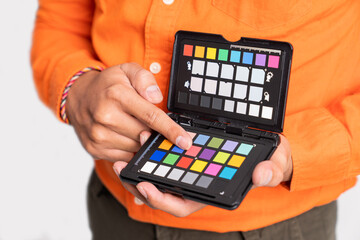 close up of photographer's hand pointing while holding color palette on isolated background