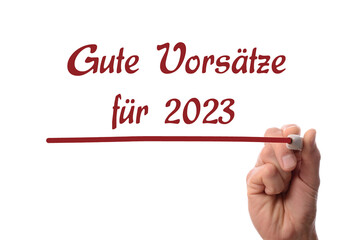 Hand with a red felt-tip pen writes the German words Good Intentions for 2023