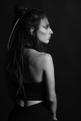 Fashion and make-up concept. Beautiful woman portrait. Model with dreadlocks and feather attached to her hair. Woman with make-up looking aside the camera. Black and white image