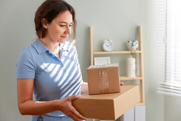 Young woman holding cardboard parcel, receiving desired delivery, getting her online order at home