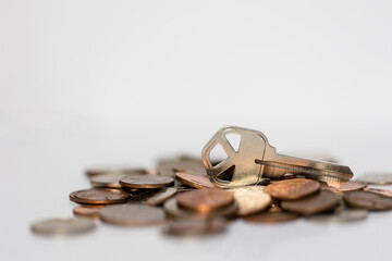 House key and stack of coins white background, investment and real-estate concept, saving money to buy a house concept