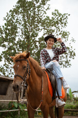 beautiful cowboy girl smiling sitting on horse on outdoor background