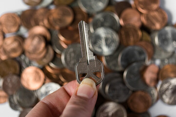 House key and stack of coins in background, investment and real-estate concept, saving money to buy a house concept