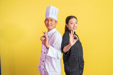 male and female chefs wearing chef jackets with okay hand gestures on isolated background