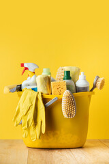 Brushes, bottles with cleaning liquids, sponges, rag and yellow rubber gloves on the yellow...