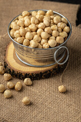 A pile of peeled hazelnuts in a metal bowl on the burlap background Healthy nutrition concept. Traditional rustic agricultural background
