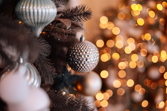 Close up view of beautiful fir branches with shiny golden bauble or ball, xmas ornaments and lights, Christmas holidays background. copy space. Decoration on christmas tree. Festive new 2024 year