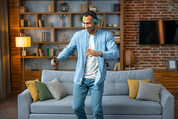 Playful man dancing alone at home and having fun. Handsome man listening to music with headphones during a relaxing day