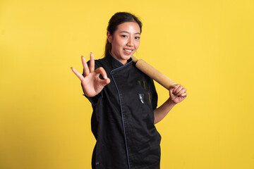 female chef holding wooden rolling pin with okay hand gesture on isolated background