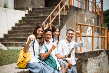 Excited high school student with fists looking at camera while gathering with his friends